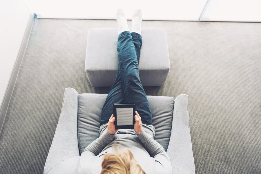 bird's eye view of person sitting in recliner reading on tablet