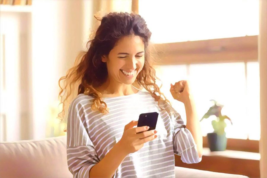 Woman pumping her fist in excitement while looking at her phone